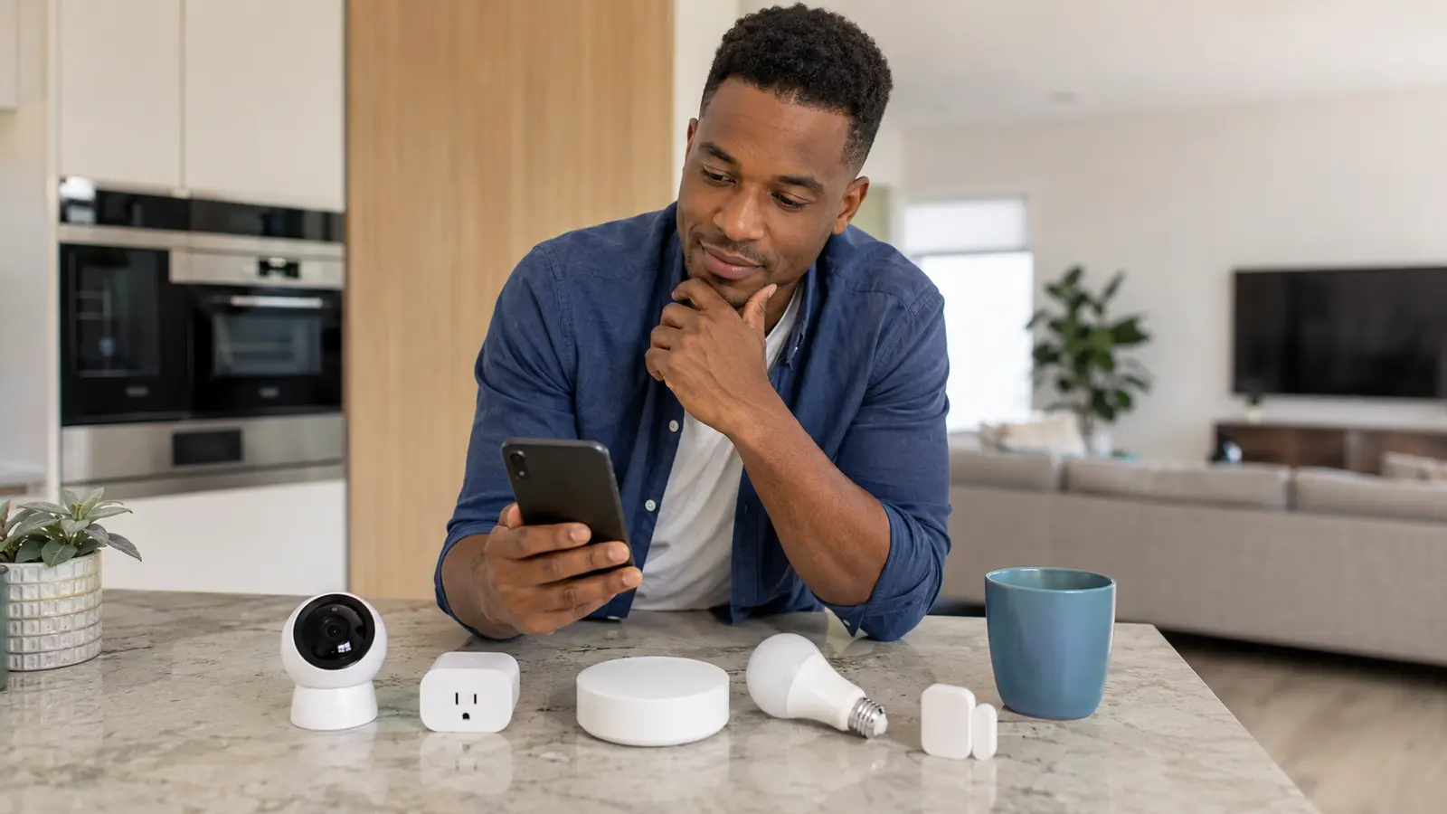 Man comparing a smart hub, camera, plug, bulb and door sensor before setting up a smart home