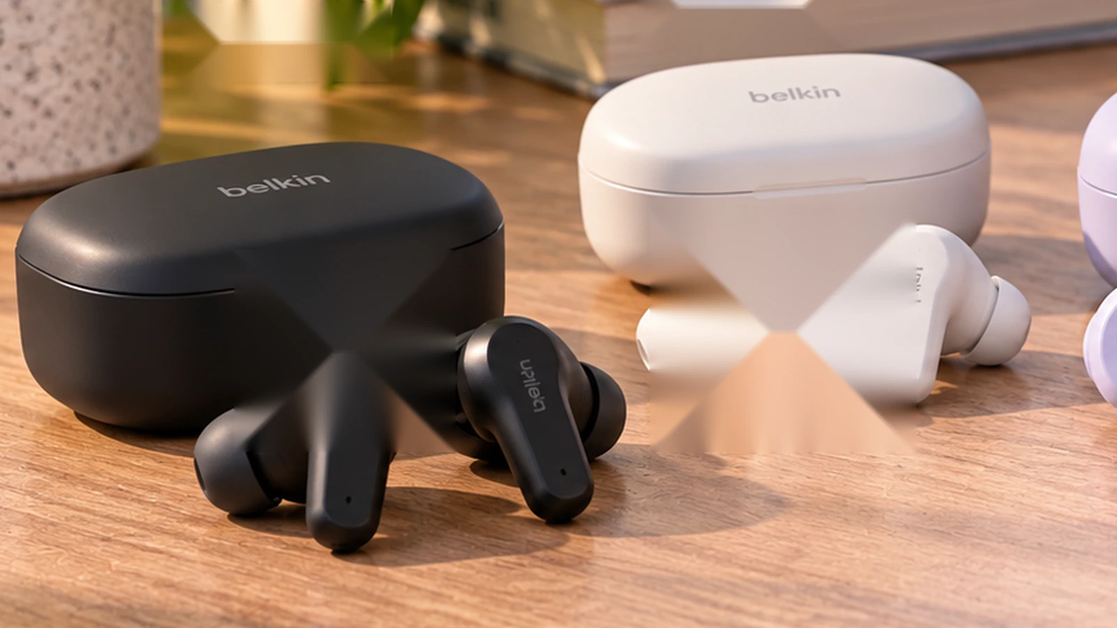 Two sets of compact wireless earbuds and charging cases on a modern desk beside everyday commuter and work accessories.