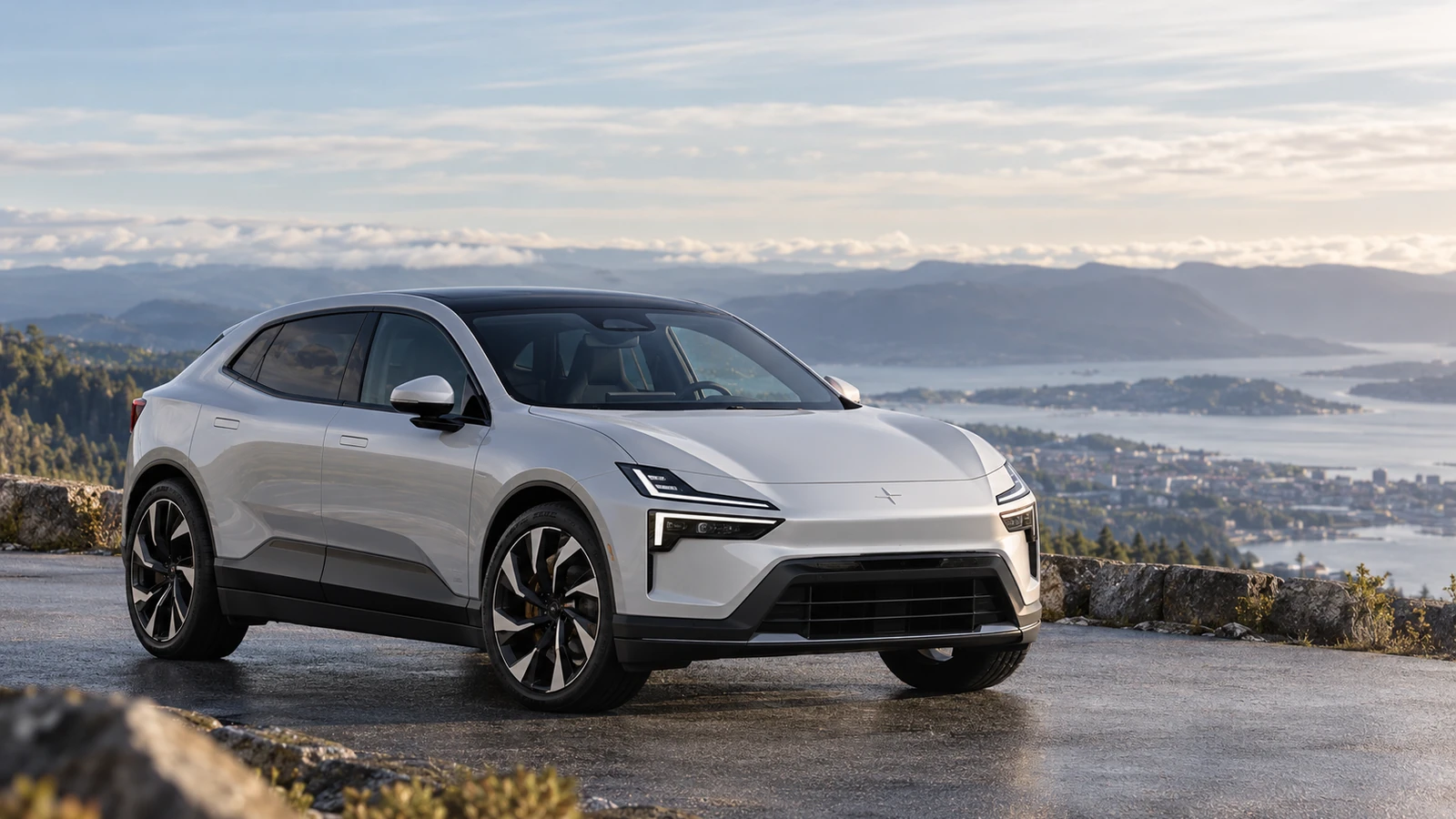 White premium electric SUV photographed on a scenic European mountain road with a practical SUV profile.